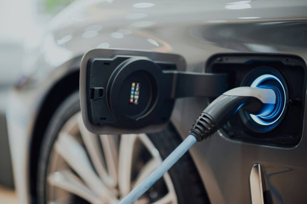 Close-up of an electric vehicle being charged, showing the charging cable plugged into the car’s charging port.
